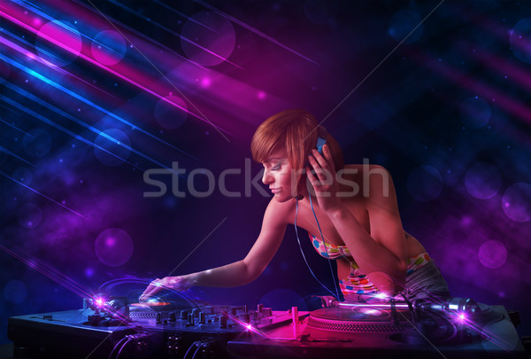 Young DJ playing on turntables with color light effects Stock photo © ra2studio