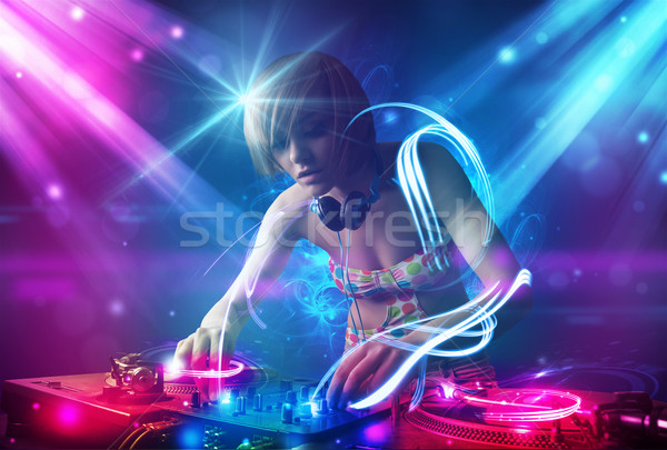 Energetic Dj girl mixing music with powerful light effects Stock photo © ra2studio
