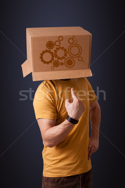 Young man gesturing with a cardboard box on his head with spur w Stock photo © ra2studio