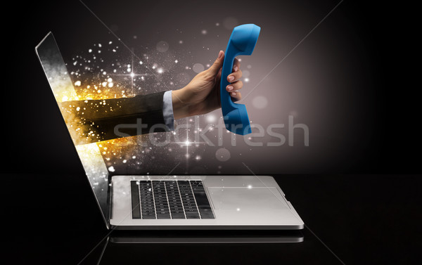 Hand with phone coming out of a laptop Stock photo © ra2studio