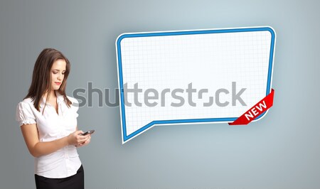 Stock photo: Beautiful young woman standing next to a modern speech bubble copy space and making phone call