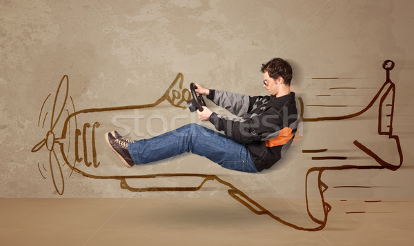 Funny pilot driving a hand drawn airplane on the wall Stock photo © ra2studio
