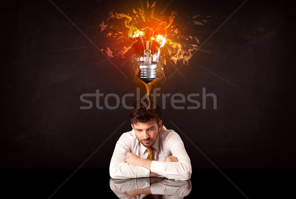 Businessman sitting under a blowing idea bulb Stock photo © ra2studio