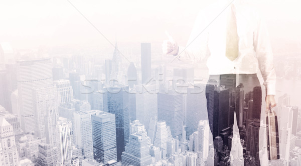 Business man standing on roof with city in the background Stock photo © ra2studio