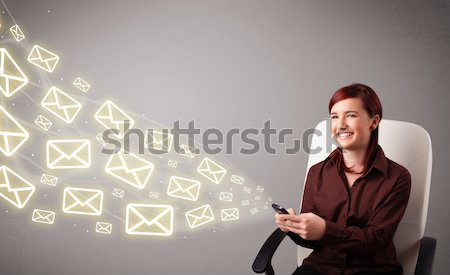 Stock photo: attractive young lady holding a phone with message icons