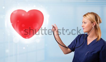 Young nurse healing a red heart Stock photo © ra2studio