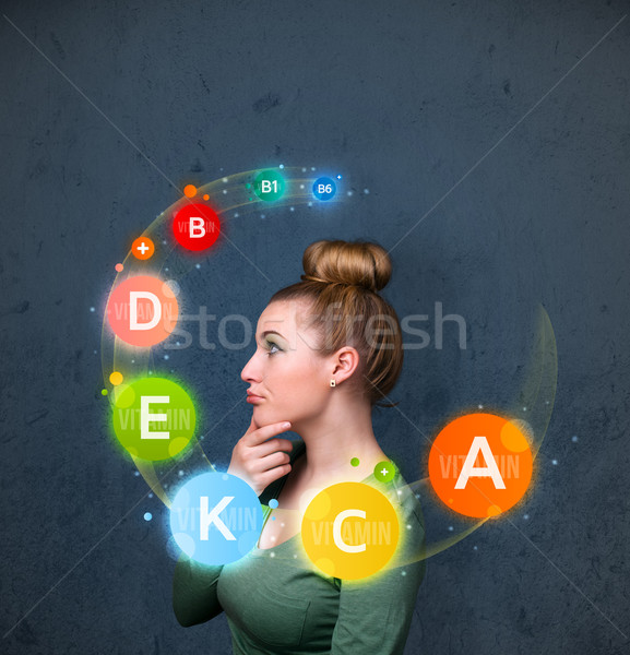 Young woman thinking with vitamins circulation around her head Stock photo © ra2studio