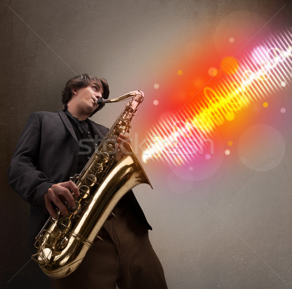 Young man playing on saxophone with colorful sound waves Stock photo © ra2studio