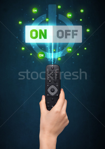 Hand with remote control and on-off signals Stock photo © ra2studio