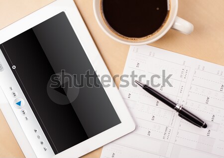 Workplace with tablet pc showing media player and a cup of coffee on a wooden work table closeup Stock photo © ra2studio
