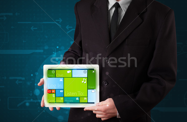 Stock photo: Young businessman holding a tablet with modern software operational system