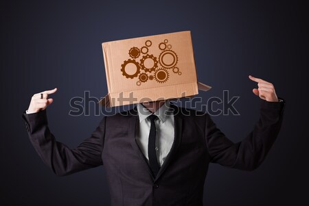 Young man gesturing with a cardboard box on his head with spur w Stock photo © ra2studio