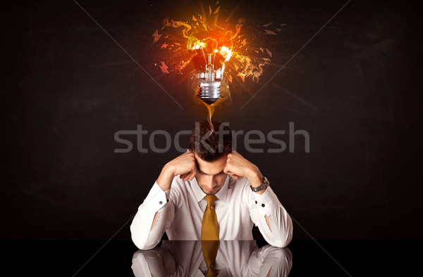 Businessman sitting under a blowing idea bulb Stock photo © ra2studio