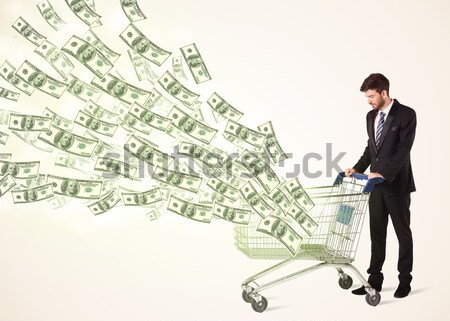 Businessman with shopping cart with dollar bills Stock photo © ra2studio