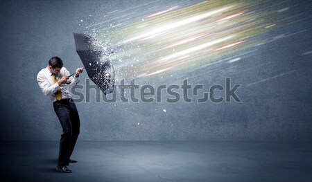 Business man defending light beams with umbrella concept Stock photo © ra2studio