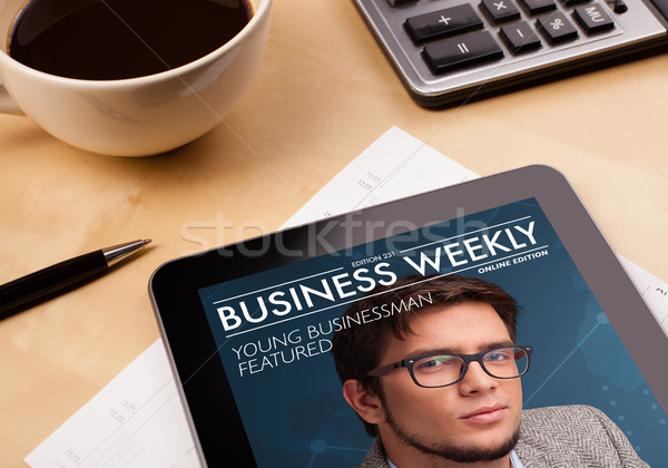 Workplace with tablet pc showing magazine cover and a cup of coffee on a wooden work table closeup Stock photo © ra2studio