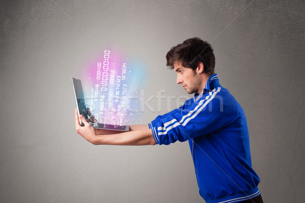 Casual man holding laptop with exploding data and numbers Stock photo © ra2studio