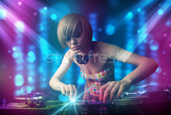 Dj girl mixing music in a club with blue and purple lights Stock photo © ra2studio