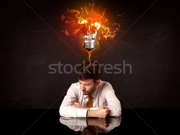 Businessman sitting under a blowing idea bulb Stock photo © ra2studio