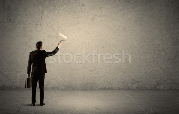 Salesman with roller standing at empty wall Stock photo © ra2studio