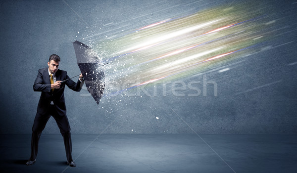 Business man defending light beams with umbrella concept Stock photo © ra2studio