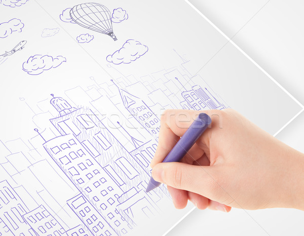 A person drawing sketch of a city with balloons and clouds on a plain paper
 Stock photo © ra2studio