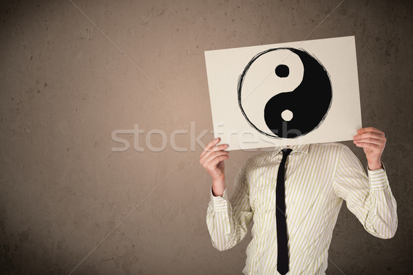Businessman holding a paper with a yin-yang on it in front of hi Stock photo © ra2studio
