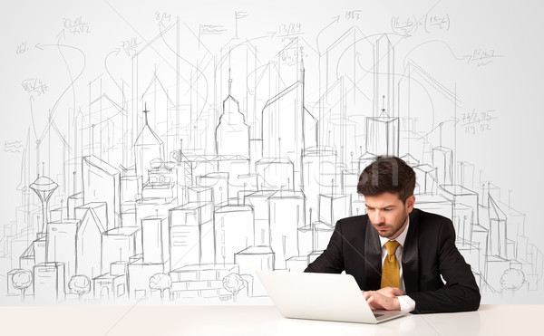 Stock photo: Businessman sitting at the white table with hand drawn buildings