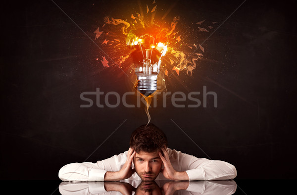 Businessman sitting under a blowing idea bulb Stock photo © ra2studio