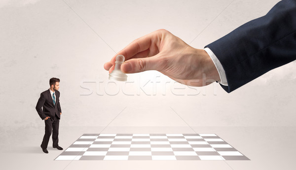 Little businessman playing chess with a big hand concept Stock photo © ra2studio