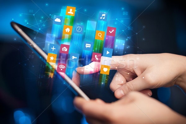 Hand using tablet with application icons flying around Stock photo © ra2studio