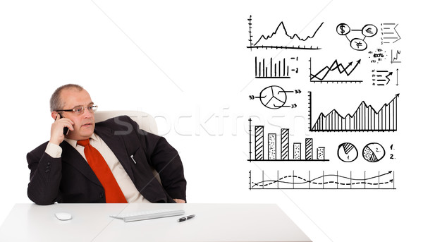 Businessman sitting at desk with diagrams and making a phone call, isolated on white Stock photo © ra2studio