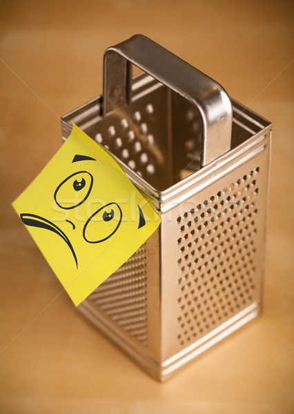 Stock photo: Post-it note with smiley face sticked on grater