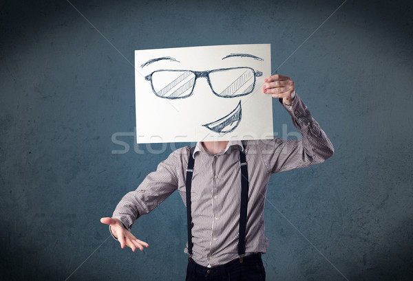 Stock photo: Businessman holding a paper with smiley face in front of his hea