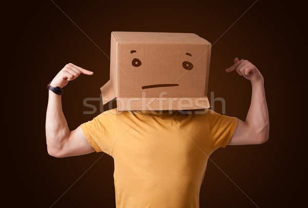 Young man gesturing with a cardboard box on his head with straig Stock photo © ra2studio