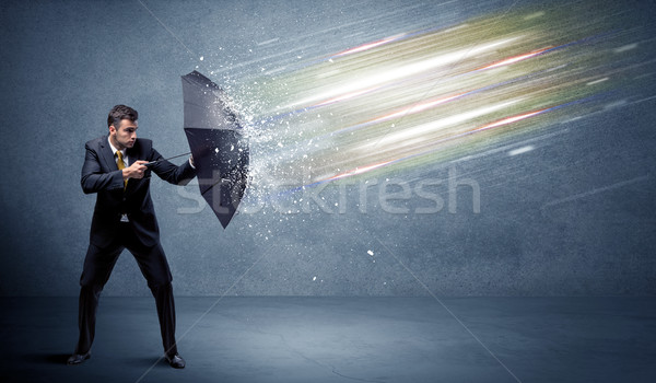 Stock photo: Business man defending light beams with umbrella concept