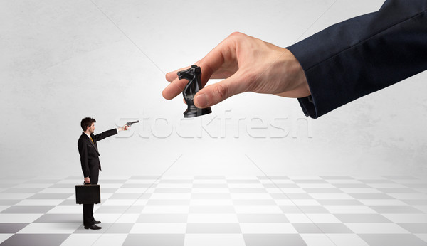 Stock photo: Businessman fighting against big chessman on a big hand