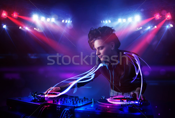 Disc jockey girl playing music with light beam effects on stage Stock photo © ra2studio