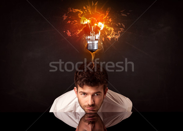 Businessman sitting under a blowing idea bulb Stock photo © ra2studio