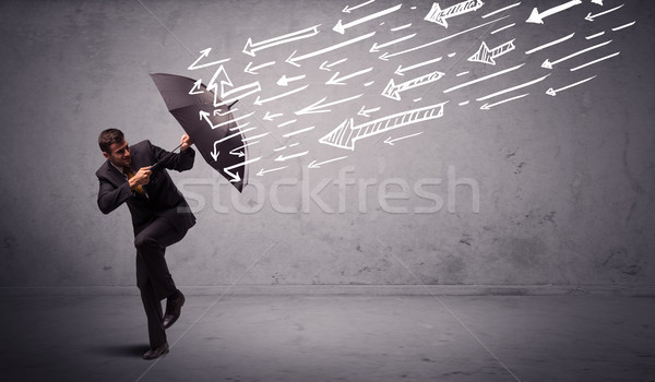 Business man standing with umbrella and drawn arrows hitting him Stock photo © ra2studio