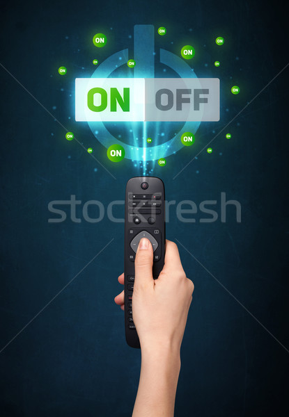 Stock photo: Hand with remote control and on-off signals