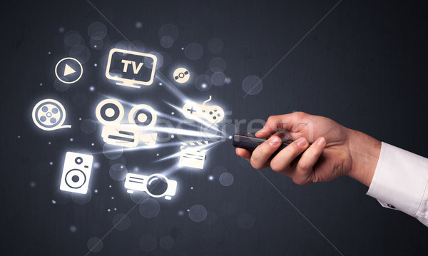 Hand with remote control and media icons Stock photo © ra2studio