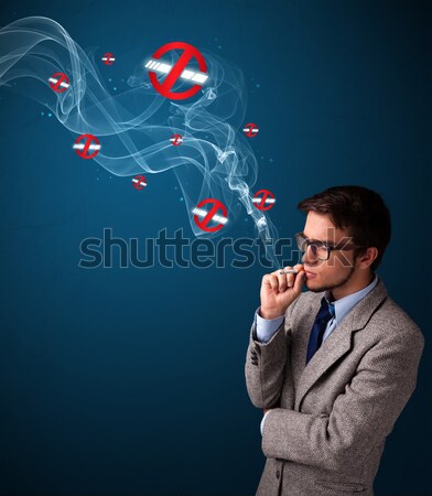 Stock photo: Attractive young man smoking dangerous cigarette with no smoking signs