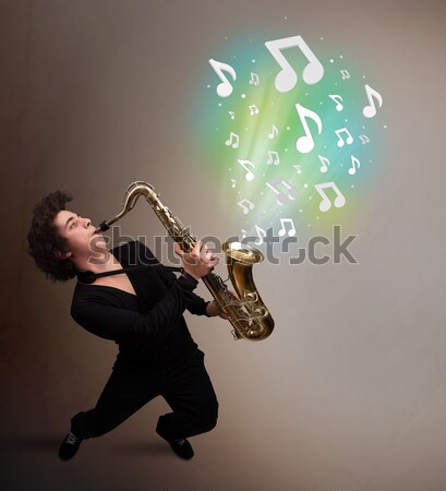 Handsome musician playing on saxophone with musical notes Stock photo © ra2studio