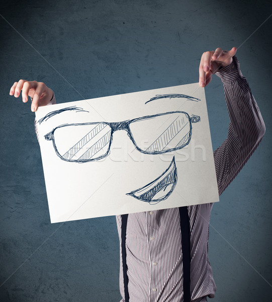 Stock photo: Businessman holding a paper with smiley face in front of his hea