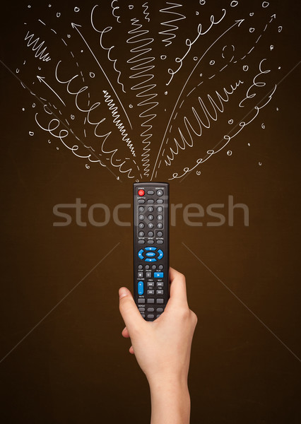 Stock photo: Hand with remote control and curly lines