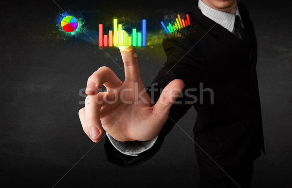 Stock photo: Handsome young business man touching colorful modern graph syste