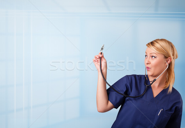 Pretty young nurse in hospital listening to empty copy space with sthetoscope Stock photo © ra2studio