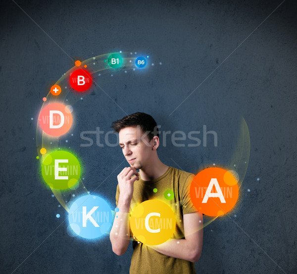 Young man thinking with vitamins circulation around his head Stock photo © ra2studio