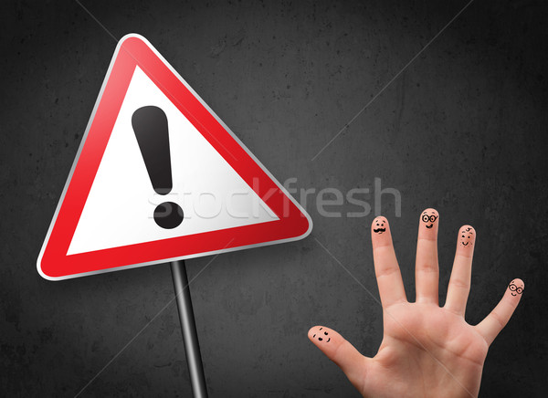 Happy cheerful smiley fingers looking at triangle warning sign with exclamation mark Stock photo © ra2studio